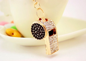 Detailed macro view of a gold whistle keychain with black and clear rhinestones