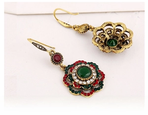 Close-up of vintage bohemian flower earrings with green stones and red crystal details