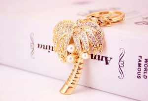 Macro shot of tropical gold palm tree keychain with sparkling rhinestones and pearl details