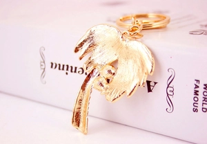 Detailed close-up of a golden tropical palm tree keychain with brushed metal texture