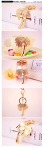 Macro detail of golden coconut tree keychain featuring crystal rhinestones and pearls
