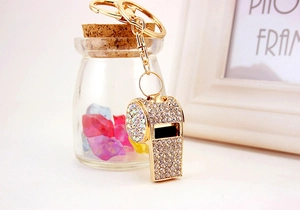 Close-up of golden whistle keychain with sparkling rhinestones on a decorative background