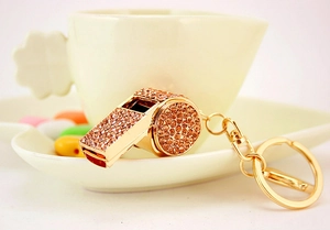 Detail of a sparkling golden whistle keychain with champagne rhinestones on a decorative tray