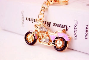 Detailed macro shot of golden motorcycle keychain with purple enamel and shiny crystals