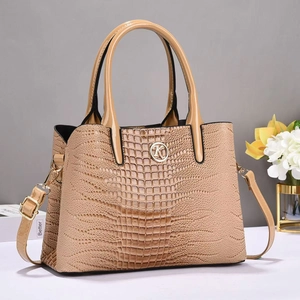 Close-up of beige crocodile pattern handbag with golden K-letter metal ring and top handles