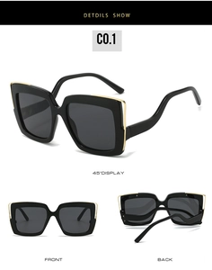 Detail view of large square sunglasses featuring black frames with gold metal edging trim