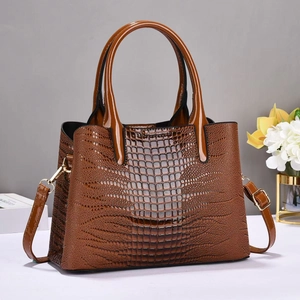 Close-up of brown crocodile-embossed leather handbag with gold metal hardware and strap