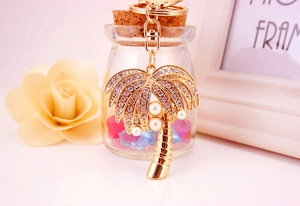 Macro detail of golden coconut tree keychain with crystal rhinestones and white pearls