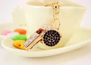 Detailed close-up of golden whistle keychain with sparkling rhinestones and metal ring