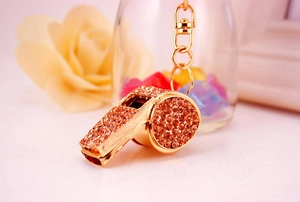 Close-up of golden whistle keychain with sparkling champagne rhinestones on flowers