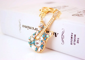 Detail shot of golden guitar keychain featuring sparkling blue and clear rhinestones