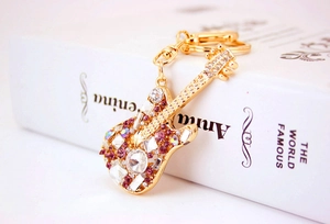 Detail of guitar keychain featuring gold-plated metal with purple and clear rhinestones