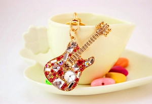 Close-up of a golden guitar keychain with sparkling red and clear rhinestones
