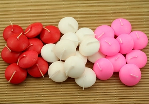 Macro shot of red, white, and pink spherical floating tea light candles on bamboo mat