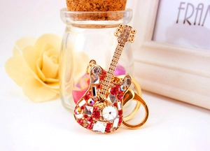 Detailed macro shot of a golden guitar keychain with sparkling red and clear rhinestones