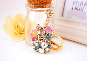 Detail of a guitar keychain with sky blue and clear crystals on a gold-plated base