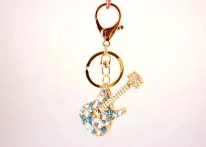 Close-up of golden guitar keychain featuring sparkling blue and white rhinestones