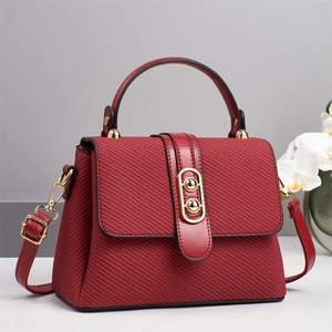 Détail du sac à main en sergé bordeaux avec finitions cuir et fermoir doré à double anneau