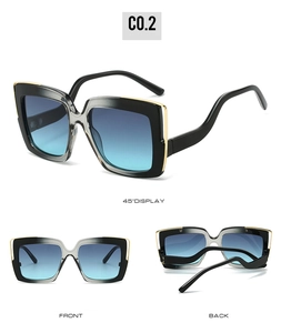 Detailed view of oversized square sunglasses with black-gray frames and gold trim