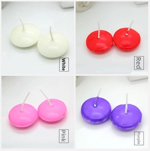 Detail showing white, red, pink, and purple floating tea light candles with cotton wicks