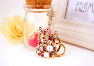 Macro shot of guitar keychain with gold metal finish and inlaid purple crystals