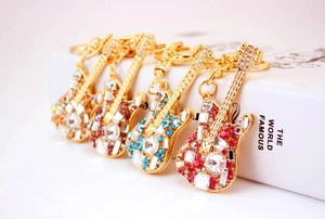 Detail of four crystal-studded guitar keychains in gold metal finish and multiple colors
