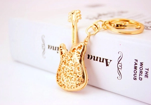 Detail shot of a golden metal guitar keychain with hollow patterns on a book surface