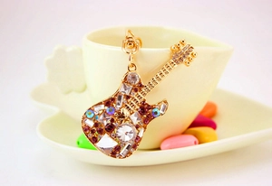 Close-up of golden guitar keychain with vibrant multicolored rhinestones and metal hook