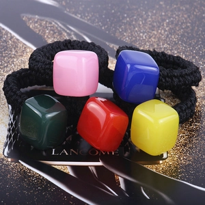 Macro detail of five colorful cube elastic hair ties in pink blue green red and yellow