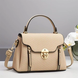 Detail of beige textured handbag with gold twist lock and vertical zippers on front