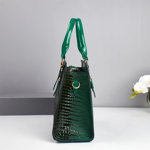 Dark green crocodile texture handbag with gold hardware shown in a minimalist setting
