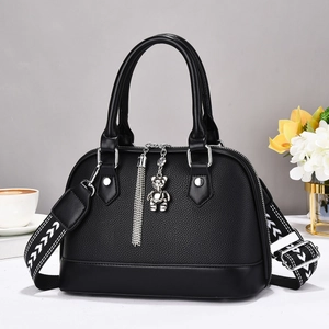 Detail of black lychee grain leather shell bag with silver bear charm and wide strap
