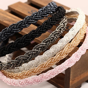 Handmade beaded braided headband set in five elegant colors on a premium wooden stand