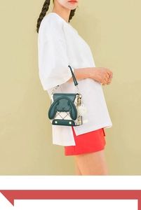 Détail du sac à main en cuir vert et pied-de-poule avec oreilles de lapin et pompon blanc
