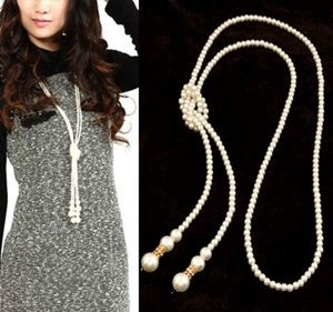 Detail of layered pearl necklace featuring decorative woven knots and golden accents