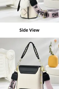 Détail du sac bandoulière crème et noir avec sangle large et pendentif pompon peluche