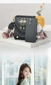 Detail of black crossbody bag with golden swan ornament and pink branded strap