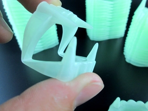 Detail shot of glowing vampire fangs prop held by hand for Halloween pranks