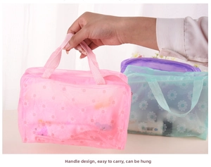 Detail showing pink PVC floral toiletry bag with daisy pattern and sturdy top handle