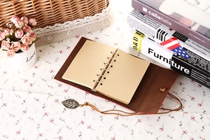 Detail of vintage brown leather notebook with metal leaf pendant and tie closure strap