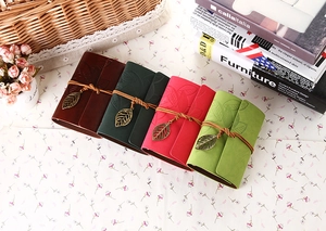 Vintage leaf pendant journals in brown, red, and green on a rustic background