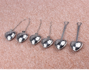 Detail of heart-shaped stainless steel tea strainers with chain and handle on pink plush
