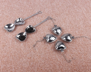 Detailed overhead view of various heart-shaped stainless steel tea strainers on a pink surface