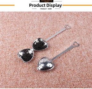 Detail view of heart-shaped stainless steel tea strainer open with loose tea leaves