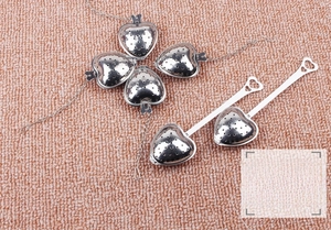 Detail of heart-shaped stainless steel tea infusers with mesh holes and long handles