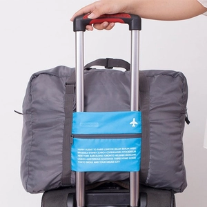 Grey foldable travel storage bag with blue luggage handle sleeve and city name design