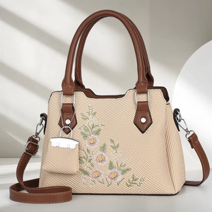 Straw woven tote bag with floral embroidery and brown leather handles in 45-degree view