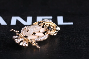 Detailed macro view of an owl brooch featuring cat eye stones and sparkling rhinestones