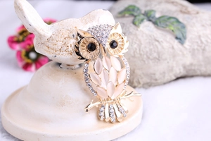 Detailed macro view of a gold owl brooch featuring cat's eye stones and crystal accents