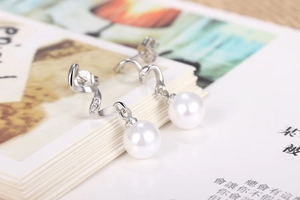Macro detail of elegant silver S-curve drop earrings with round white pearls and zircons